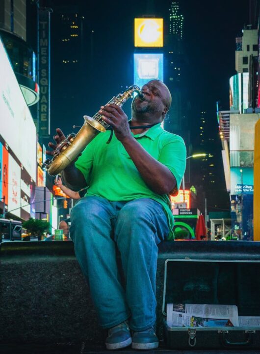 pexels-photo-3525688 Street musician playing saxophone in vibrant Times Square, NYC by night.