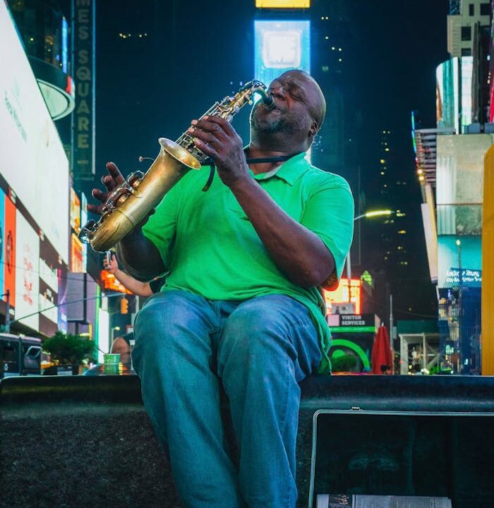 Street musician playing saxophone in vibrant Times Square, NYC by night.